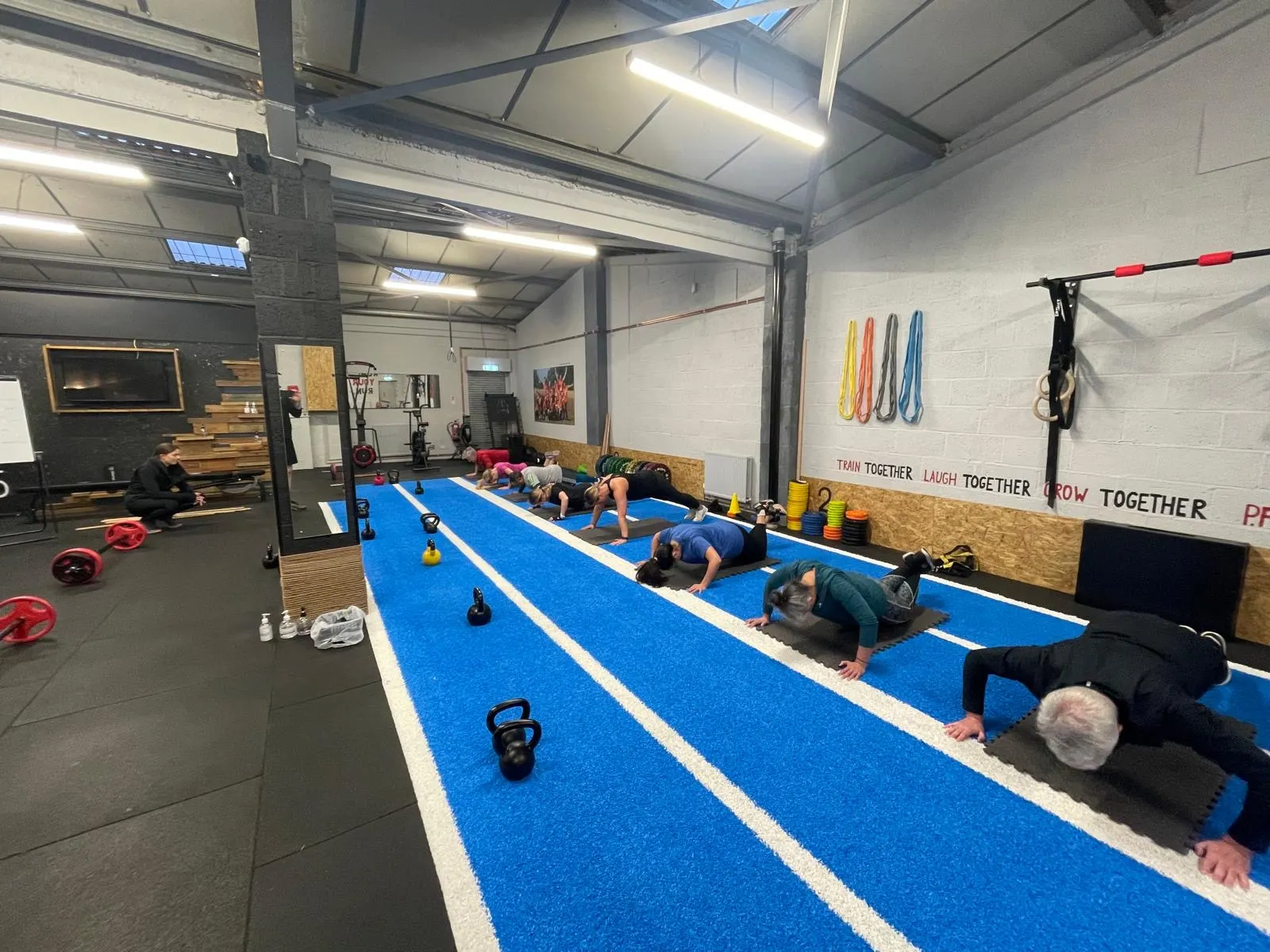 Physical Formula early indoor gym, members training on the blue floor with the Train Together wall behind them