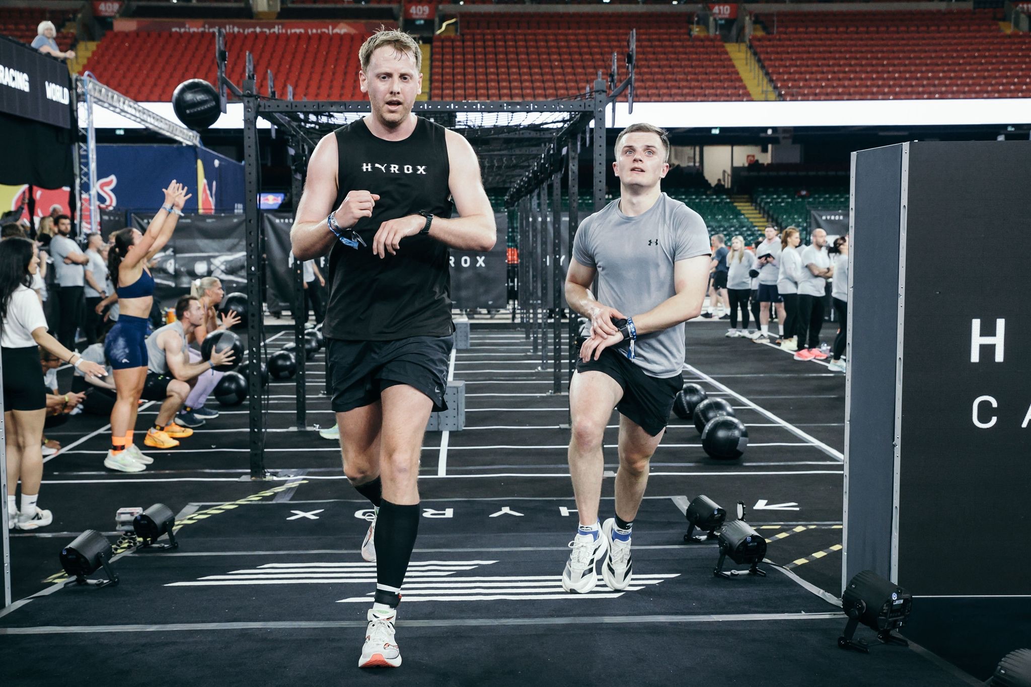 Athletes pacing the indoor running loop at a HYROX race venue