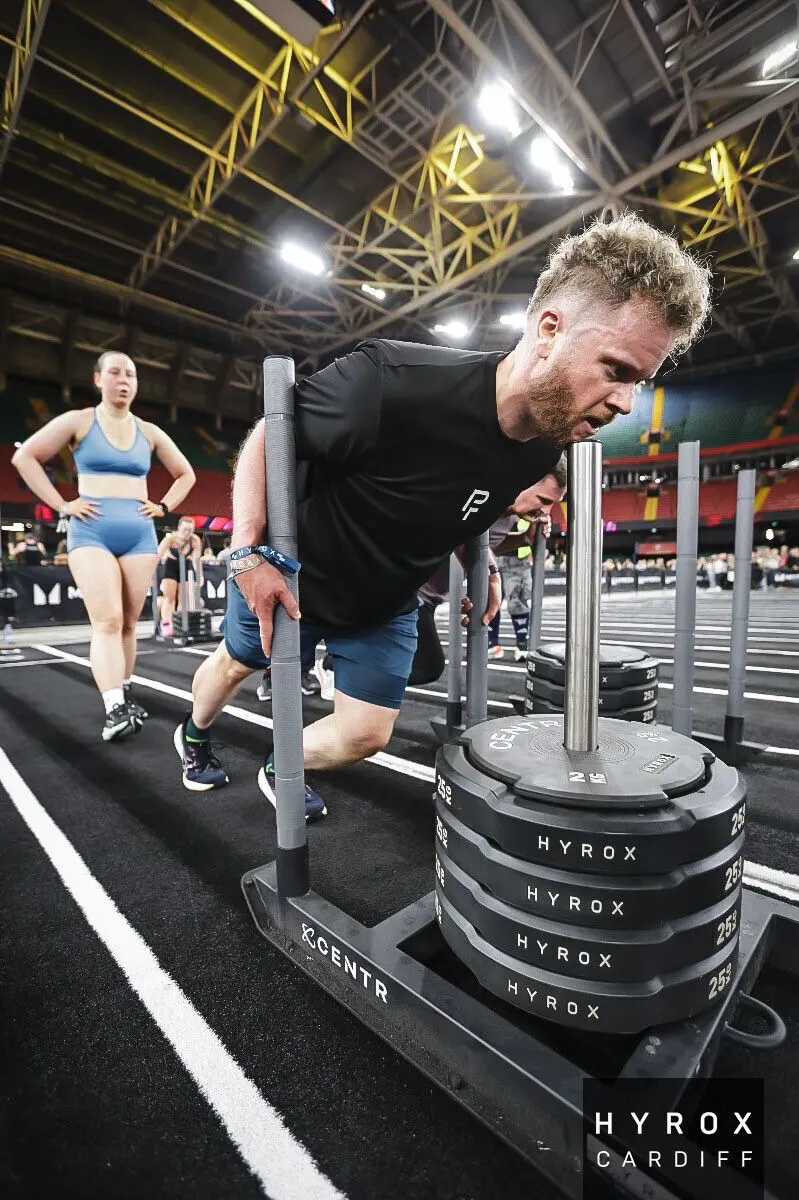 Ed on the sled push at HYROX Cardiff, in his Physical Formula top